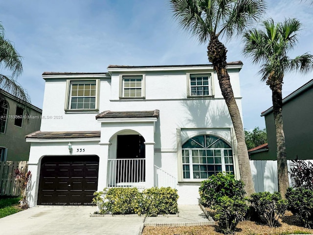 view of front of house with stucco siding, driveway, a garage, and fence