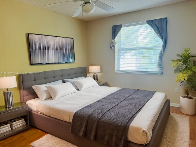 bedroom with a ceiling fan, wood finished floors, and baseboards