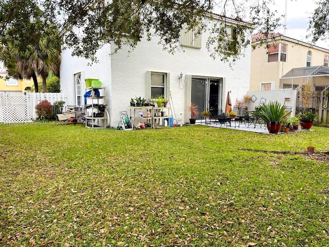 rear view of property featuring stucco siding, a yard, fence private yard, and a patio area