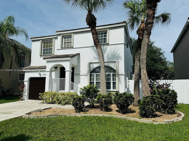 view of front of property with a front yard, fence, driveway, stucco siding, and a garage