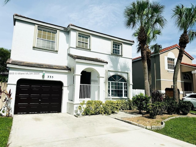 view of front facade featuring a tiled roof, stucco siding, an attached garage, and driveway