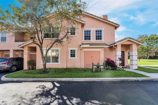 view of front of property featuring a tile roof, a front yard, and stucco siding