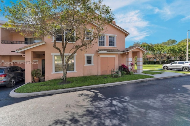 view of front of property with stucco siding, a front yard, and a tiled roof