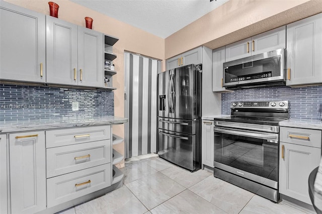 kitchen featuring light stone counters, backsplash, stainless steel appliances, and open shelves