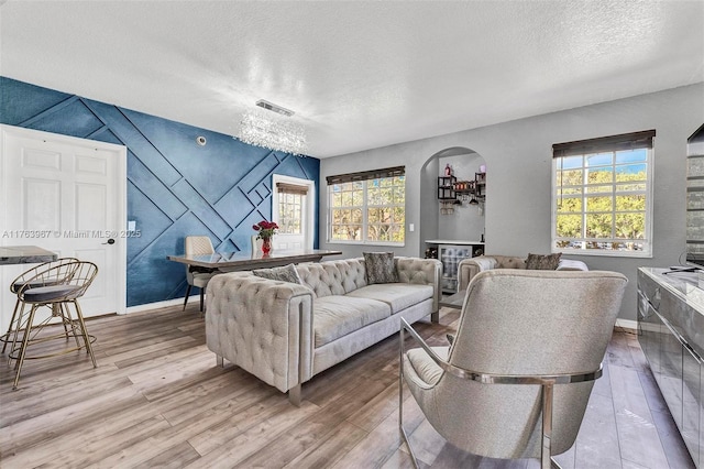 living area with visible vents, baseboards, a textured ceiling, and wood finished floors