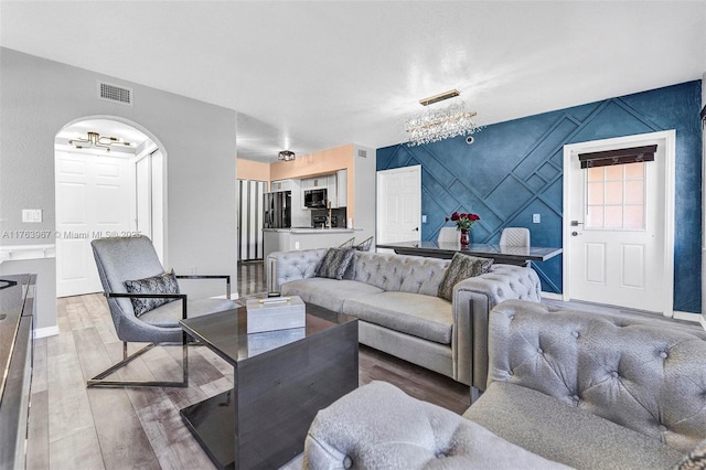 living room with visible vents, baseboards, wood finished floors, and an accent wall