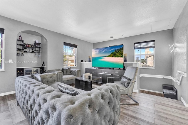 living area with plenty of natural light, a textured ceiling, baseboards, and wood finished floors