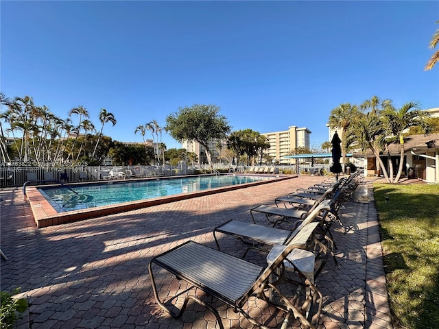 community pool with a patio and fence