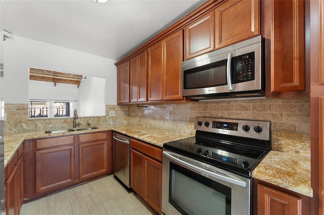 kitchen with light stone countertops, a sink, decorative backsplash, appliances with stainless steel finishes, and brown cabinets