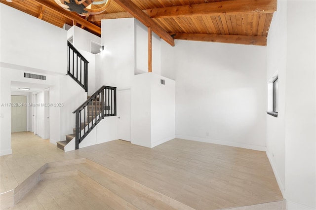 interior space featuring beam ceiling, visible vents, stairway, and wood finished floors