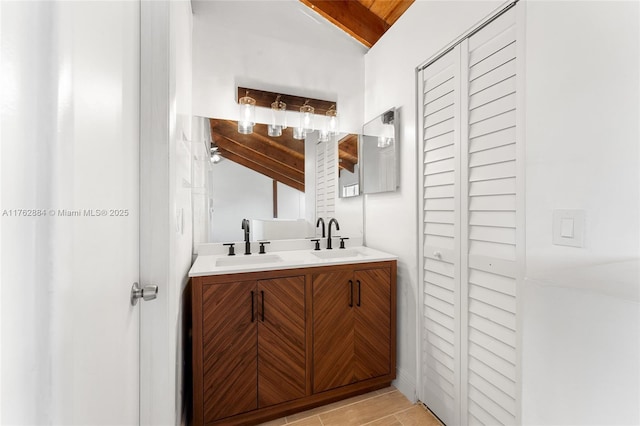 bathroom with a sink, double vanity, and vaulted ceiling with beams