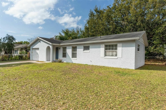 ranch-style home featuring a front yard, an attached garage, concrete driveway, and stucco siding