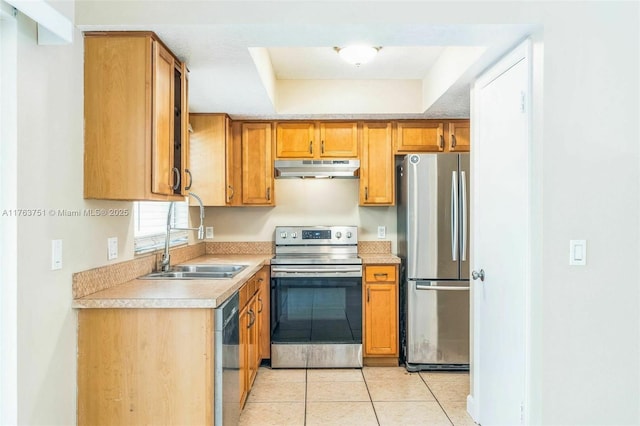 kitchen featuring under cabinet range hood, light countertops, light tile patterned floors, stainless steel appliances, and a sink