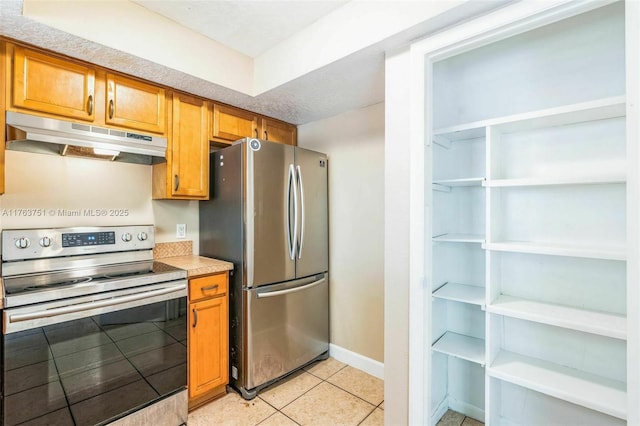 kitchen with baseboards, under cabinet range hood, light countertops, appliances with stainless steel finishes, and light tile patterned flooring