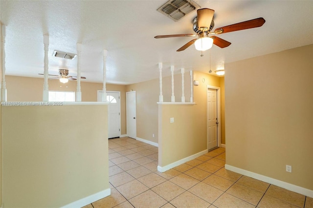 spare room with light tile patterned floors, a ceiling fan, visible vents, and baseboards