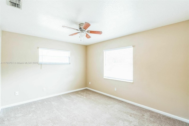 spare room with visible vents, baseboards, a ceiling fan, and carpet flooring