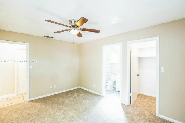 unfurnished bedroom featuring visible vents, connected bathroom, a walk in closet, baseboards, and carpet floors