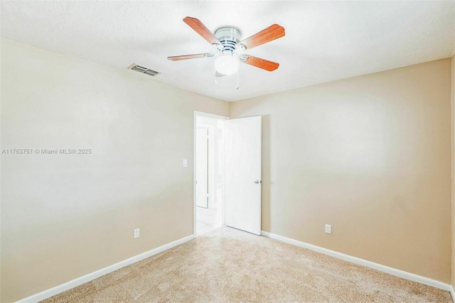 carpeted spare room featuring a textured ceiling, baseboards, visible vents, and ceiling fan