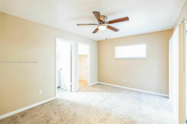 unfurnished bedroom with a walk in closet, a closet, carpet, baseboards, and ceiling fan