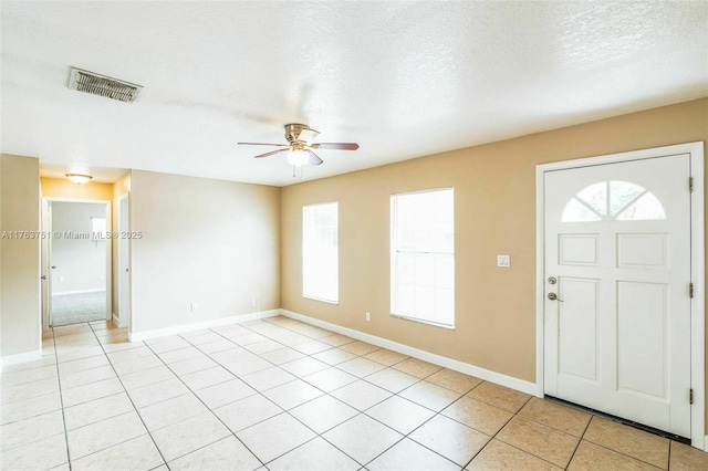 foyer featuring light tile patterned floors, a ceiling fan, baseboards, visible vents, and a textured ceiling