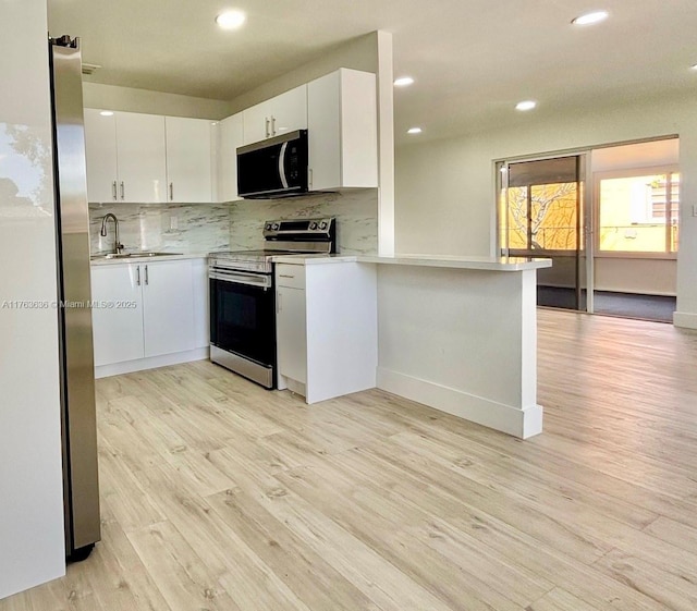 kitchen with a sink, tasteful backsplash, stainless steel appliances, white cabinets, and light countertops