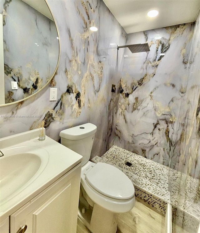 full bathroom featuring a marble finish shower, toilet, and vanity