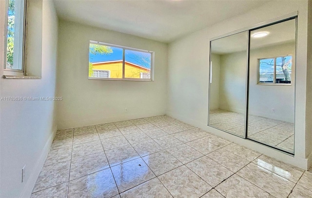 unfurnished bedroom with tile patterned floors, multiple windows, and a closet