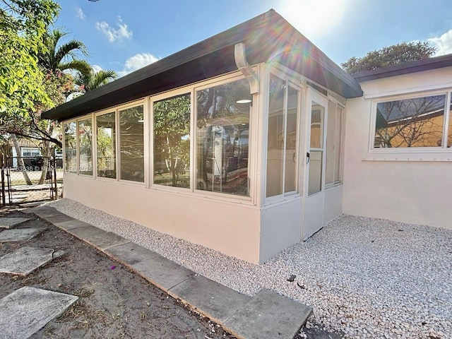 view of side of property featuring a sunroom and stucco siding