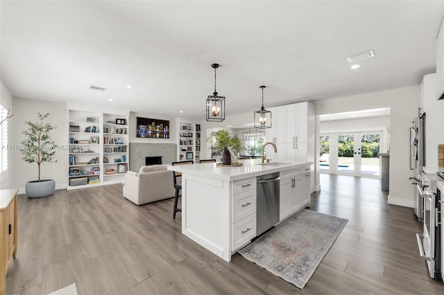 kitchen featuring a center island with sink, visible vents, a fireplace, a sink, and stainless steel dishwasher