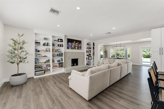 living room featuring visible vents, baseboards, a high end fireplace, and light wood finished floors