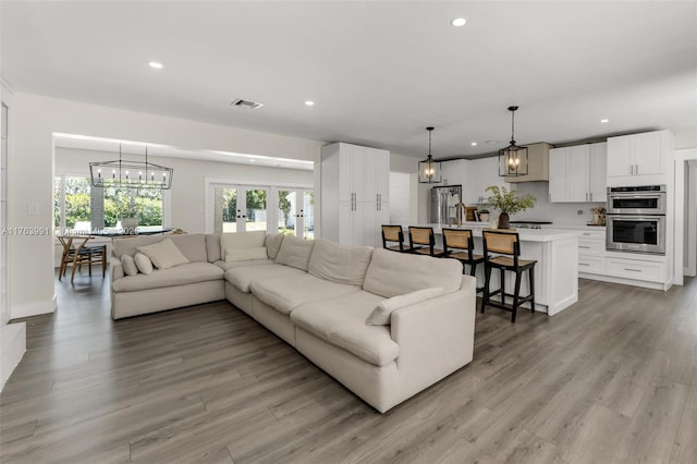 living room featuring recessed lighting, visible vents, a chandelier, and light wood-style flooring