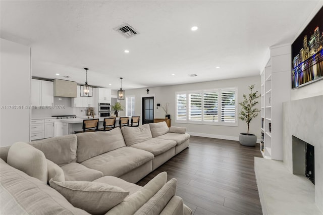 living room with visible vents, baseboards, a premium fireplace, recessed lighting, and dark wood-style floors