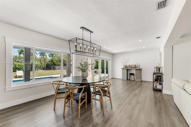 dining area with a notable chandelier, visible vents, and wood finished floors