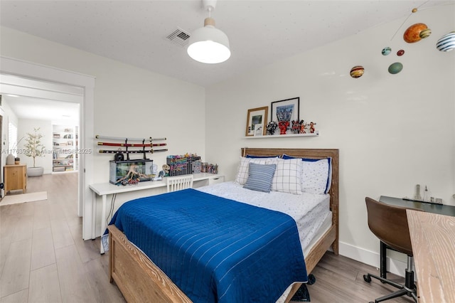 bedroom featuring visible vents, baseboards, and wood finished floors