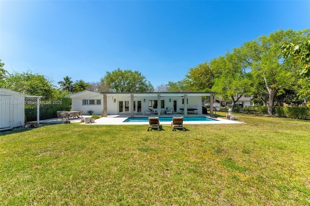 back of property with a patio, a yard, and an outdoor pool