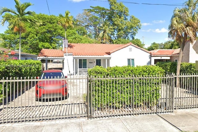 mediterranean / spanish-style house featuring a tiled roof, a gate, a fenced front yard, and stucco siding