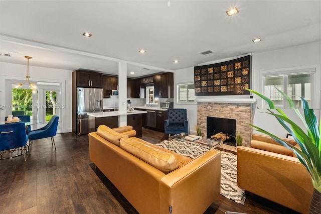 living room with visible vents, dark wood finished floors, a toaster, a stone fireplace, and recessed lighting