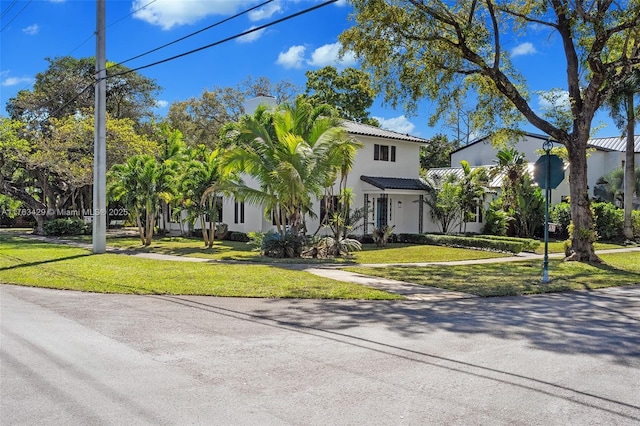 view of front of property featuring stucco siding, a tiled roof, and a front yard