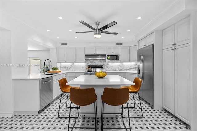 kitchen featuring a sink, a breakfast bar area, under cabinet range hood, and appliances with stainless steel finishes