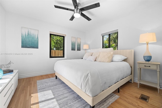 bedroom with a ceiling fan, baseboards, light wood-style floors, and visible vents