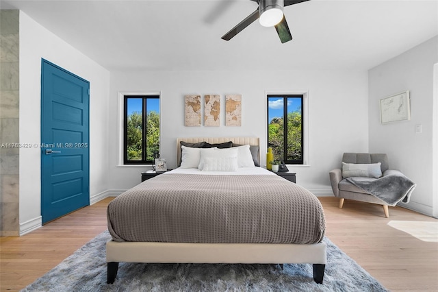 bedroom with wood finished floors, multiple windows, and a ceiling fan