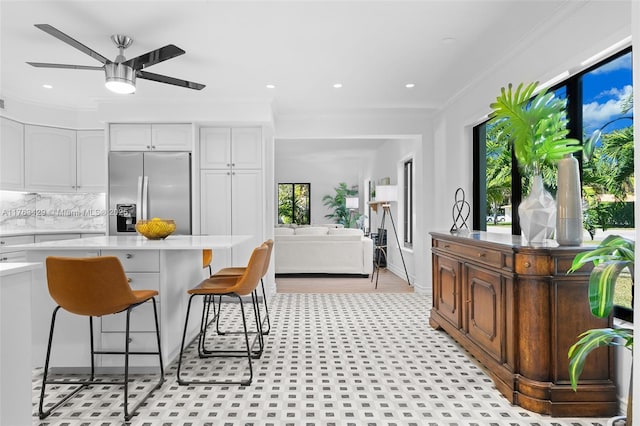 kitchen with a ceiling fan, light countertops, ornamental molding, and stainless steel refrigerator with ice dispenser