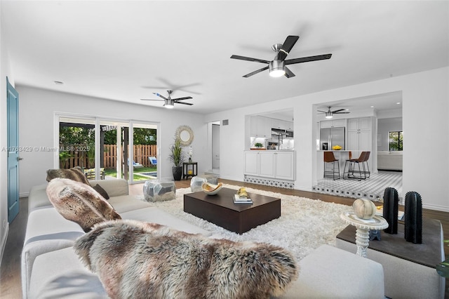 living area with baseboards, wood finished floors, and a ceiling fan