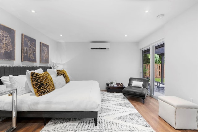 bedroom with a wall mounted air conditioner, access to exterior, wood finished floors, and recessed lighting