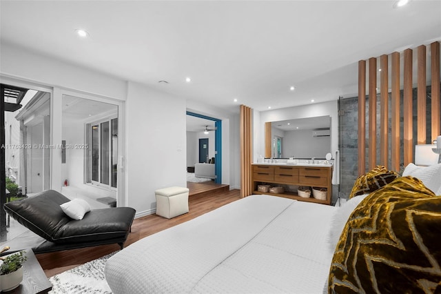 bedroom with recessed lighting, an AC wall unit, baseboards, and wood finished floors