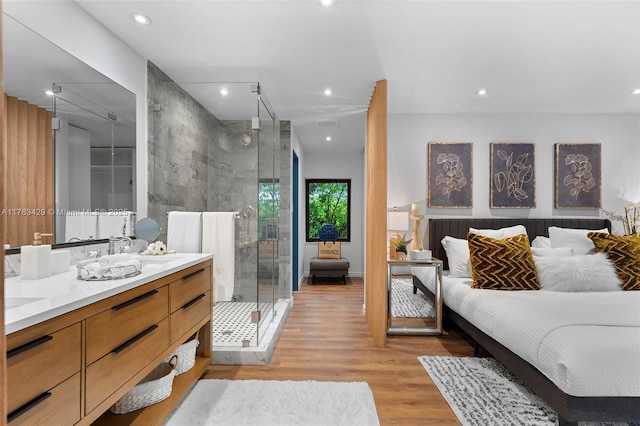 full bath with a shower stall, double vanity, wood finished floors, recessed lighting, and a sink