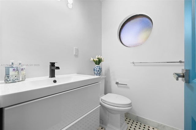 bathroom with toilet, vanity, and baseboards