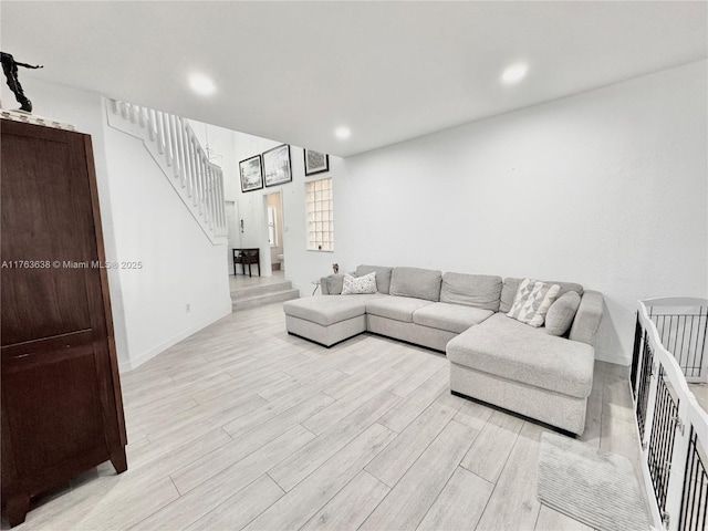 living room featuring recessed lighting, light wood-type flooring, and stairs