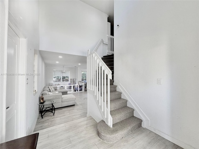 stairway with a high ceiling and wood finished floors