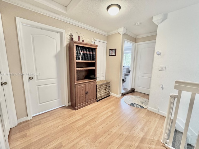 interior space with light wood-style flooring, a textured ceiling, baseboards, and ornamental molding